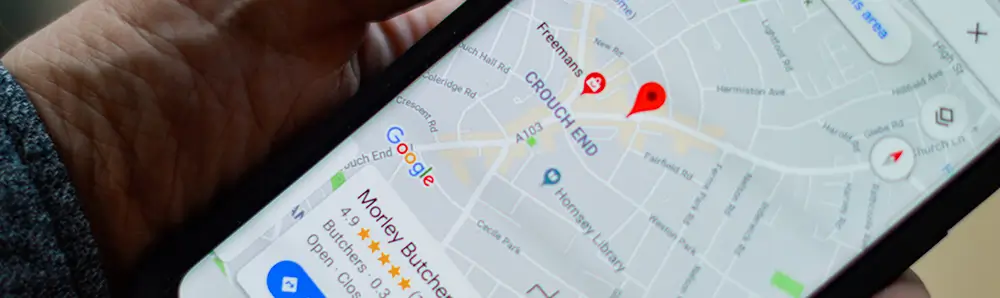 Photo d'une personne tenant un smartphone avec Google Maps et une fiche Google Business Profile