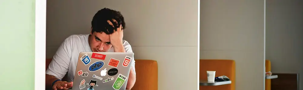 Homme se tenant la tête devant un ordinateur portable
